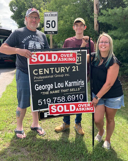 Clients of George Lou Karmiris standing with the sold sign.