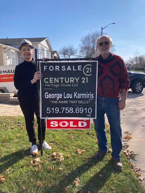 Home buyers standiing with a sold sign from George Lou Karmiris.